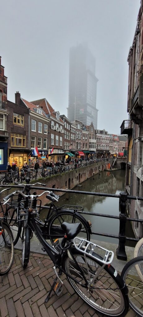 A bike sits in front of a canal in Utrecht as the fog covers the Dom Tower